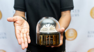 A disembodied pair of hands holding the Kirkus Prize trophy